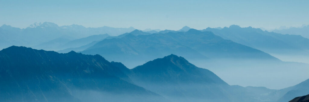 A serene, layered mountain range covered in soft blue mist, representing the calm, objective clarity of a secure retirement journey with Havend's RetireSURE framework.