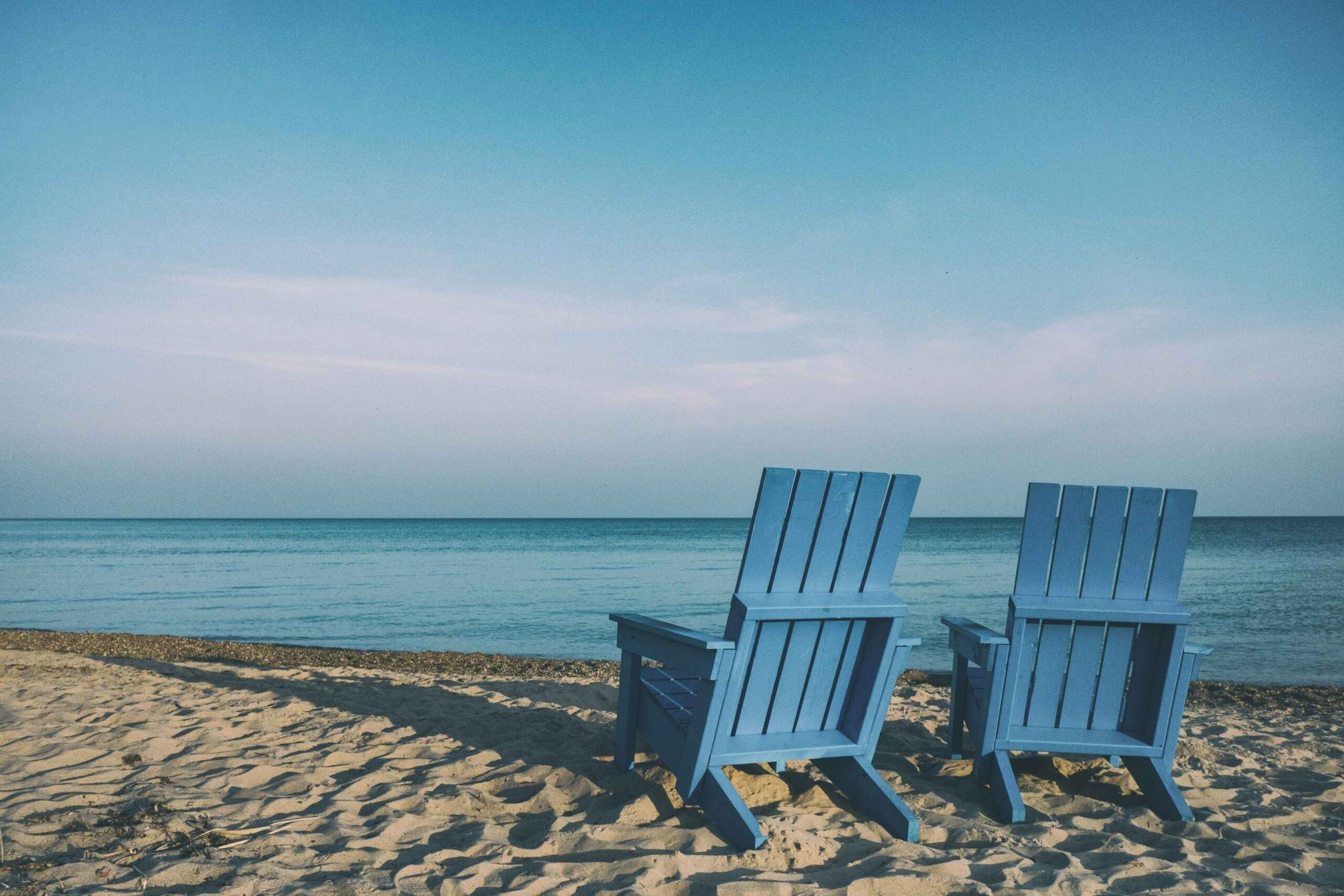 Two empty beach chairs facing a calm sea at dusk — representing the quiet confidence of a well-planned retirement in Singapore